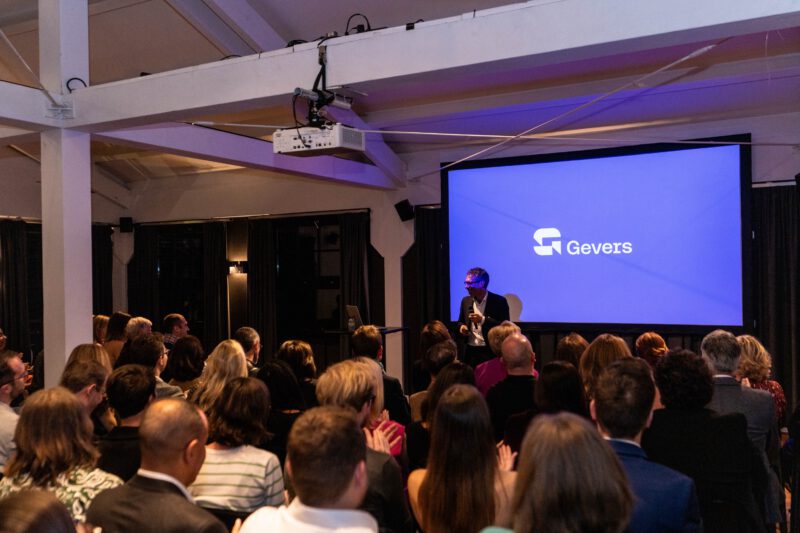 Bram Dejan, managing partner, is giving a presentation to his team of intellectual property experts. He is standing in front of a screen, on which the logo of Gevers is shown.